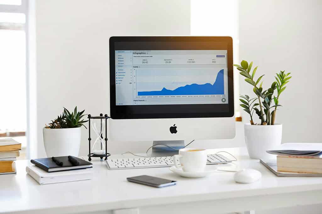 pexels-photo-572056-572056 A clean, contemporary workspace featuring a desktop with analytics on the screen and plants for a fresh look.